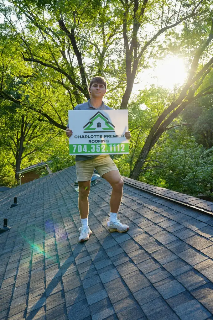 Charlotte Premier Roofing yard sign held up on a finished shingle roof