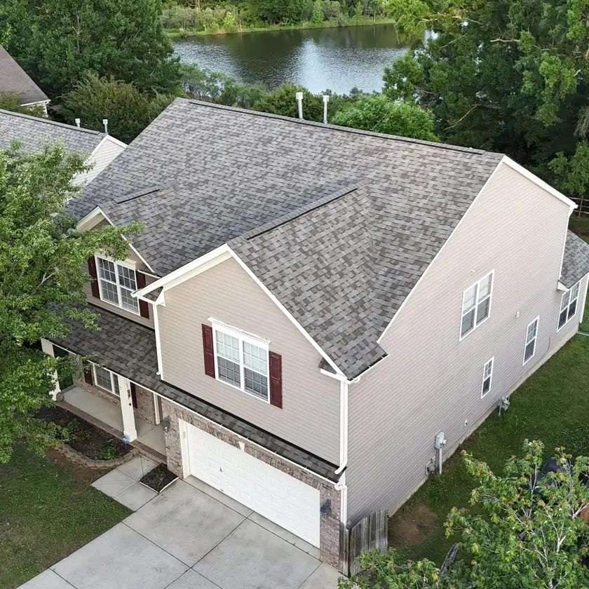 Drone view of a new architectural shingle roof on a two-story home backing onto a pond