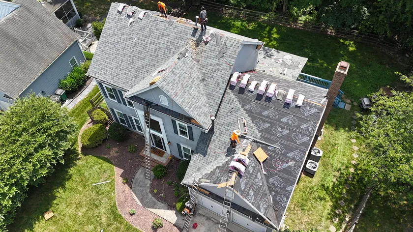 Drone view of our crew tearing off old shingles and laying new underlayment on a two-story home in Ballantyne, Charlotte