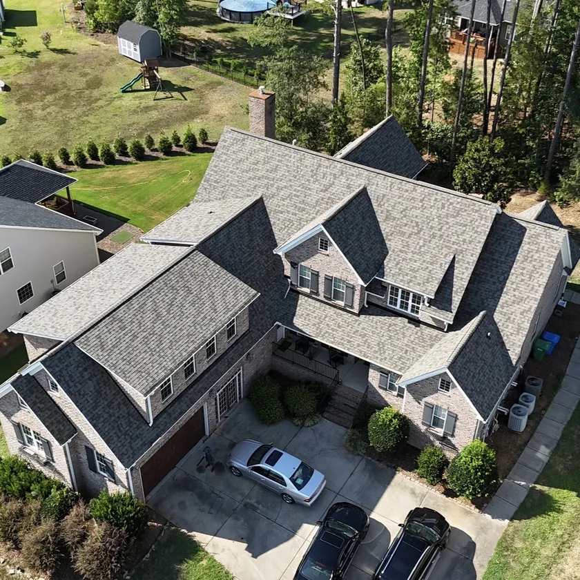 Drone view of an architectural shingle roof with several gables on a large brick home in Waxhaw, NC