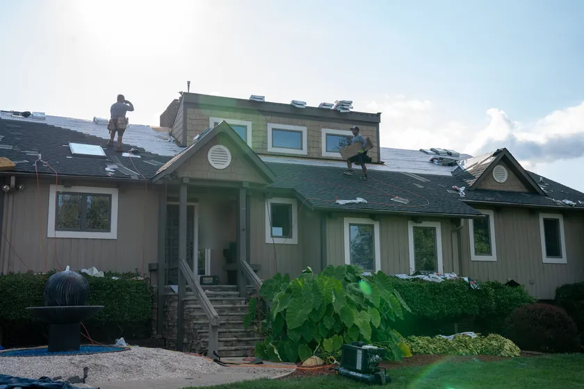 Two of our crew on the roof of a home in Cornelius, with the old shingles coming off and new underlayment going down