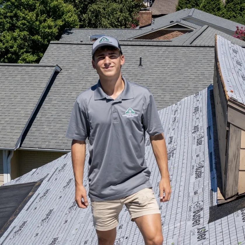 Matthew Zhuk, owner of Charlotte Premier Roofing, standing on new synthetic underlayment during a roof replacement