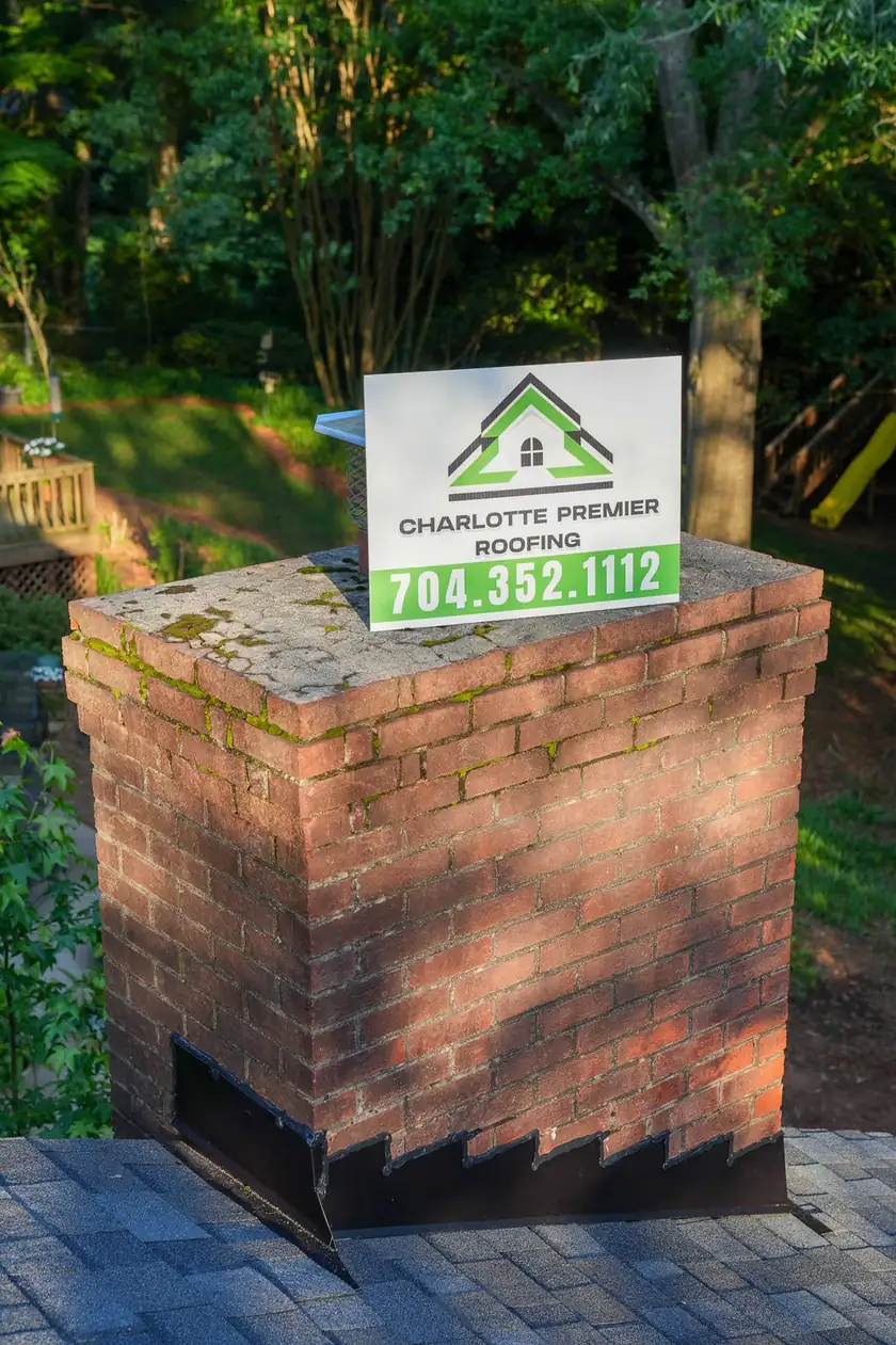 Charlotte Premier Roofing yard sign propped on a brick chimney crown