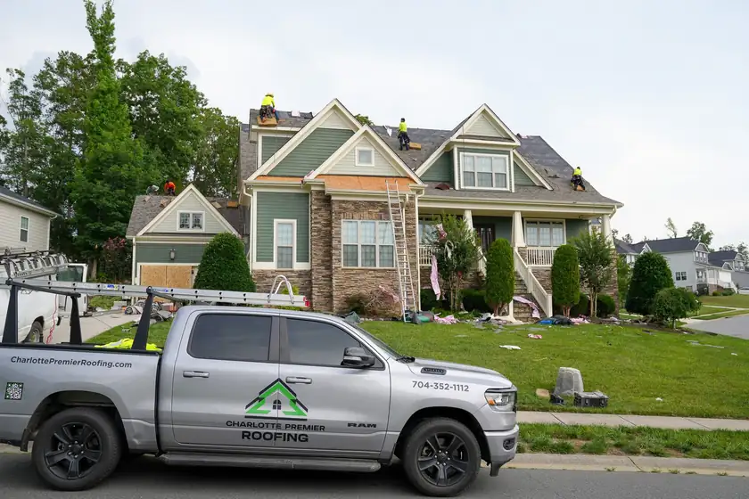 Charlotte Premier Roofing truck at the curb while the crew tears off the roof of a two-story home