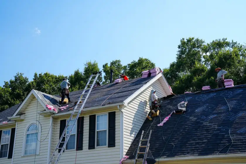 Charlotte Premier Roofing crew laying charcoal shingles over black synthetic underlayment on a two-story home