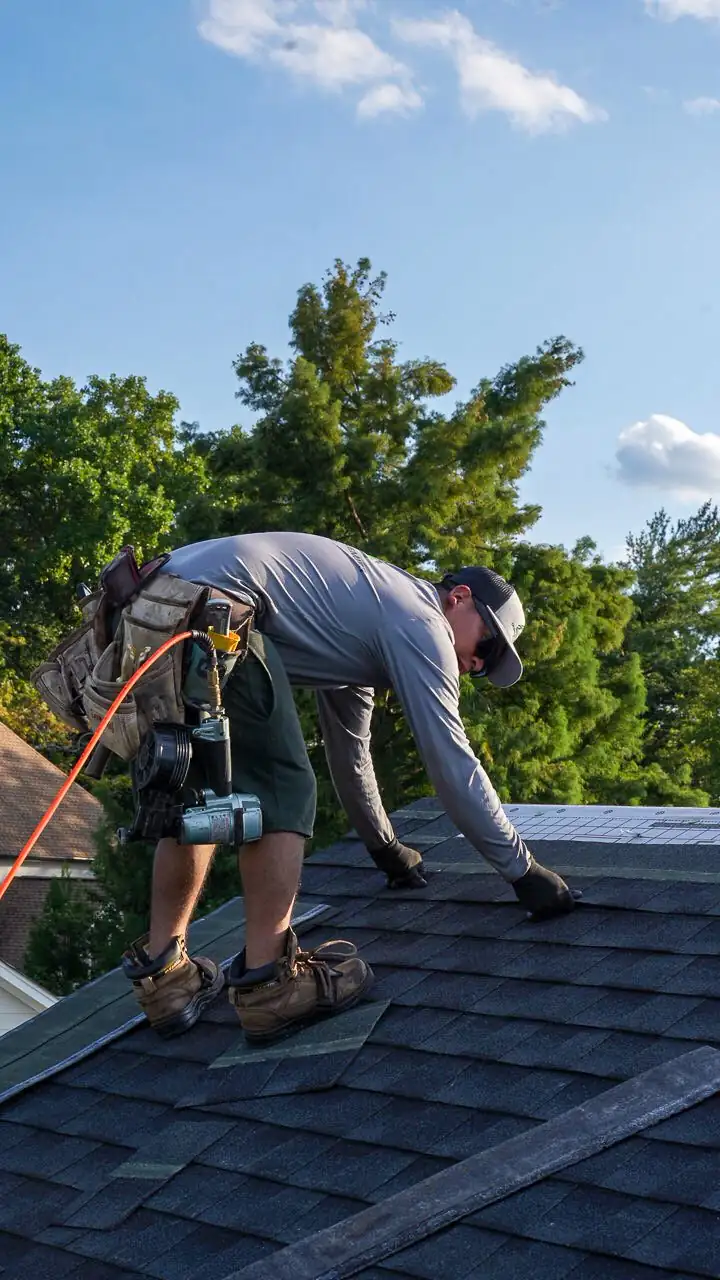 Charlotte Premier Roofing roofer setting an architectural shingle, nail gun on his belt