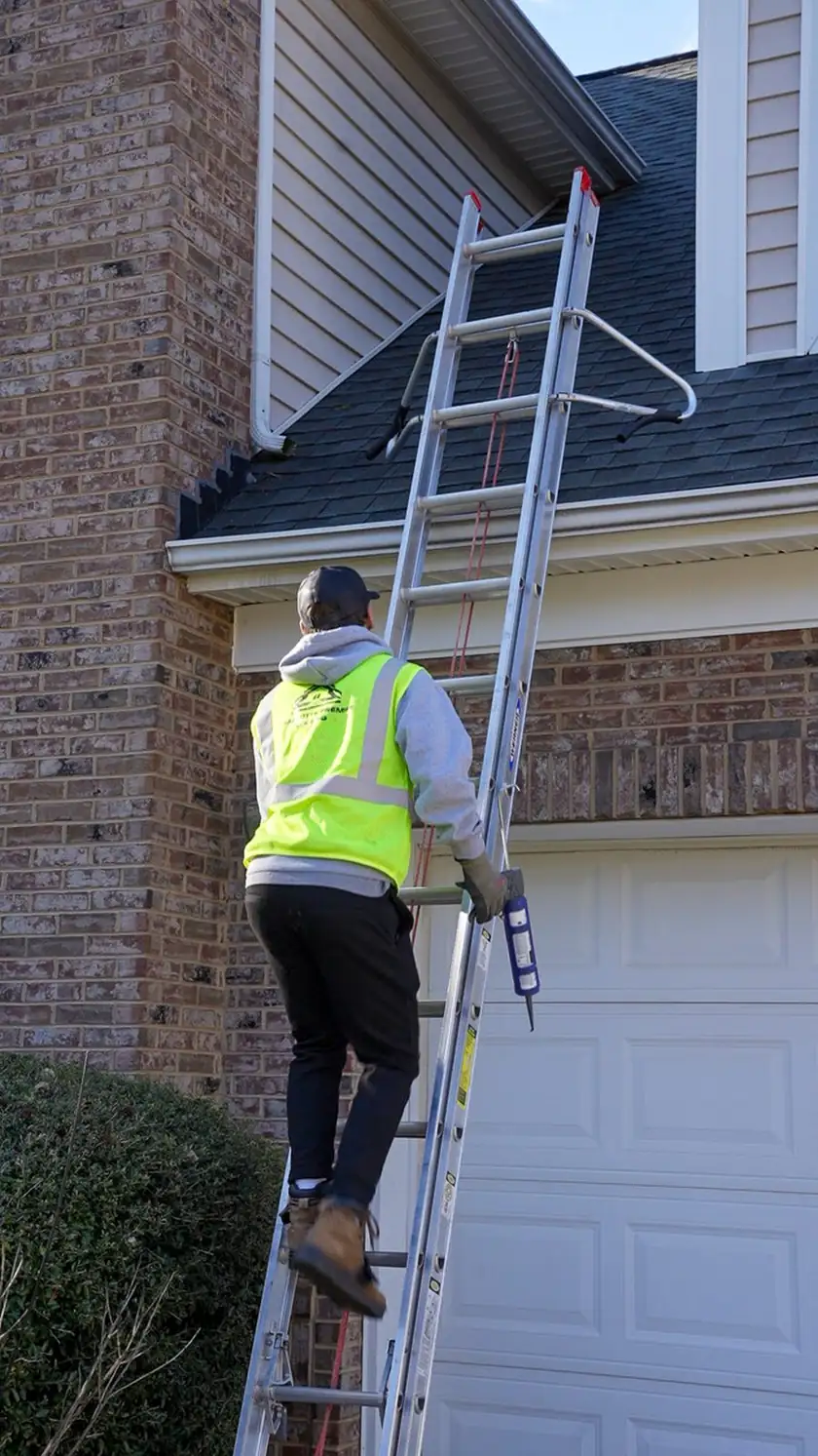 Charlotte Premier Roofing crew member climbing an extension ladder with a tube of sealant