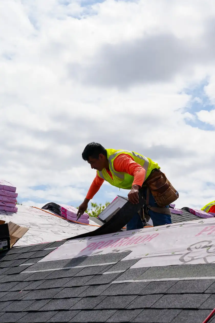 Charlotte Premier Roofing roofer pulling a strip of synthetic underlayment across a roof deck