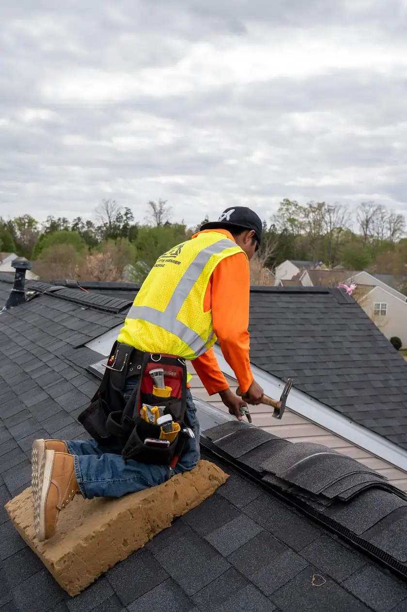 Charlotte Premier Roofing roofer hammering ridge cap along the ridge line of a shingle roof