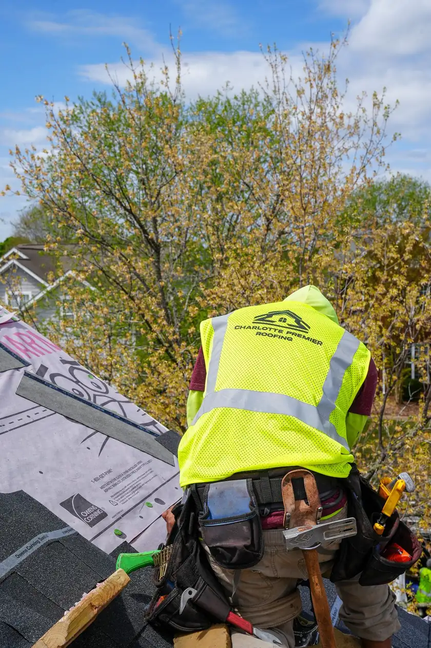 Charlotte Premier Roofing roofer kneeling beside Owens Corning underlayment on a roof deck
