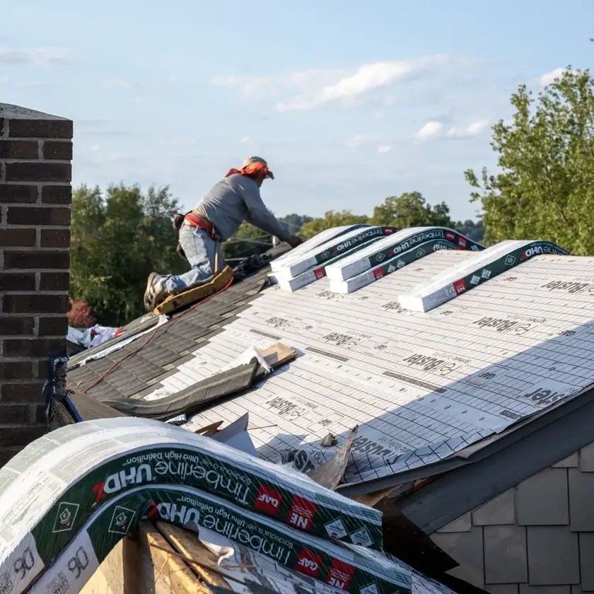 Charlotte Premier Roofing roofer stocking shingle bundles on the ridge over new synthetic underlayment