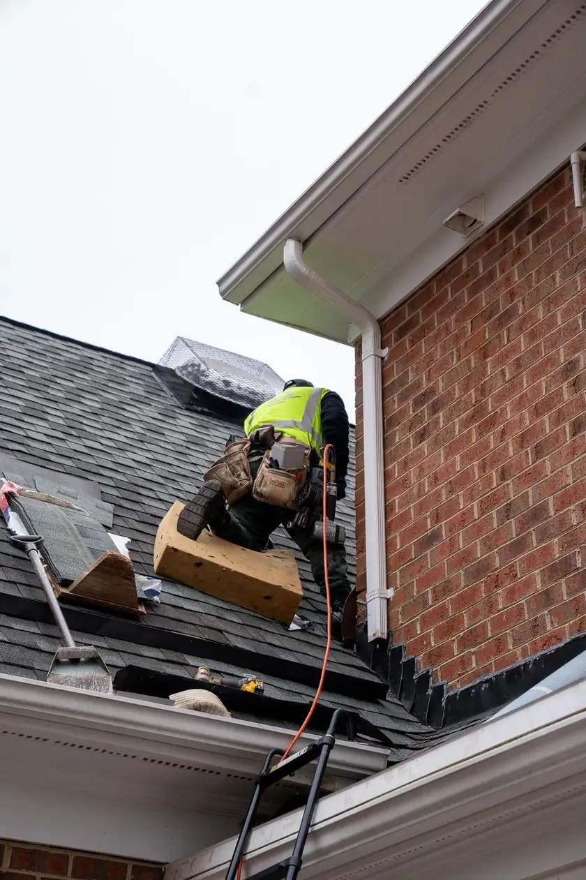 Charlotte Premier Roofing roofer fitting step flashing where a lower roof meets a brick wall in Weddington, NC