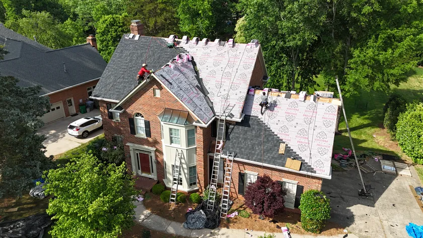 Drone view of our crew re-roofing a two-story brick home in Charlotte, NC, with new underlayment going down