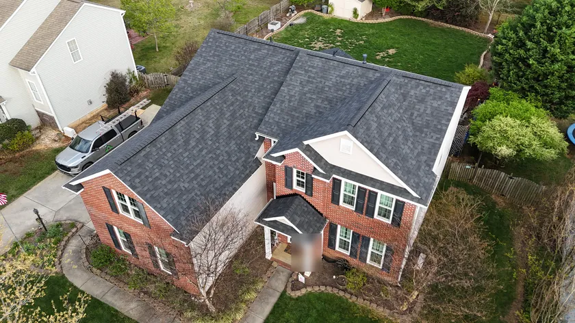 Drone view of a finished charcoal shingle roof on a brick home in Union County, NC, with our truck in the driveway