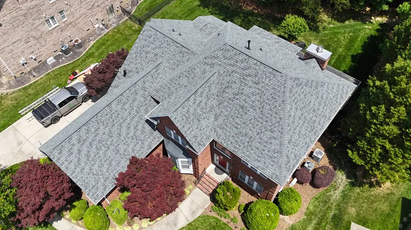 Drone view of a finished light grey shingle roof on a brick home in Waxhaw, NC, with our truck in the driveway